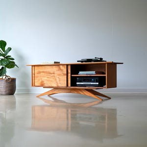May include: A mid-century modern wooden media console with a sliding door and open shelving. The console features a turntable on top and a stereo receiver on the shelf. The console is supported by a unique, angled base.
