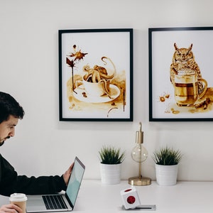 Puede incluir: Dos impresiones de arte de caf&eacute; enmarcadas en una pared blanca. La impresi&oacute;n de la izquierda presenta un pulpo en una taza de caf&eacute; con un dise&ntilde;o de mancha de caf&eacute;. La impresi&oacute;n de la derecha presenta un b&uacute;ho bebiendo caf&eacute; de una taza.