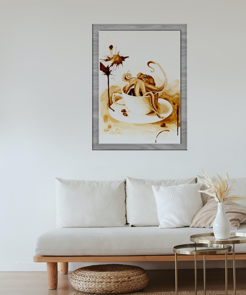Puede incluir: Una pintura de acuarela de un pulpo en una taza de caf&eacute;. El pulpo es marr&oacute;n y tiene ocho tent&aacute;culos. La taza de caf&eacute; es blanca y tiene un platillo. La pintura est&aacute; enmarcada en un marco de madera claro.