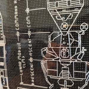 K&ouml;nnte beinhalten: Ein Schwarzwei&szlig;diagramm des Apollo 11-Mondmoduls mit dem Text "LUNAR MODULE - COMMAND MODULE" und "DESCENT - ASCENT - COM - XO".