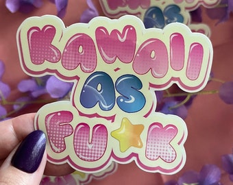 May include: A sticker with the text "Kawaii as F*ck" in pink, blue, and yellow bubble letters with a star in the middle. The sticker has a white background with a dotted pattern.