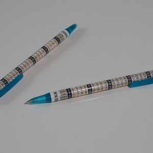 Pode incluir: Duas canetas azuis com um design de calendário branco e números pretos. As canetas têm uma tampa azul e um corpo branco.