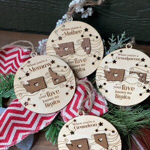 May include: Four wooden Christmas ornaments with a state outline and a heart in the center. Each ornament has a different title: "When you're a Mother", "When you're a Memaw", "When you're a Grandparent", and "When you're a Grandma". Each ornament also has the text "your love knows no limits".