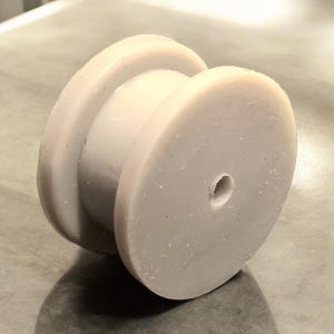 May include: A white plastic spool with a hole in the center. The spool has a smooth, slightly textured surface.