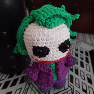 K&ouml;nnte beinhalten: Geh&auml;keltes Pl&uuml;schtier des Jokers aus Batman, mit gr&uuml;nen Haaren, wei&szlig;em Gesicht, lila Jacke und schwarzen Augen.