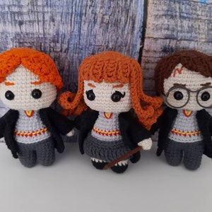 May include: Three crocheted stuffed toys of Harry Potter characters. The characters are Harry Potter, Ron Weasley, and Hermione Granger. The toys are all wearing their Hogwarts school uniforms.
