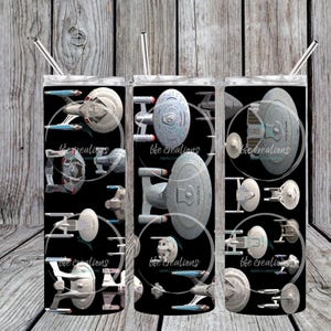May include: Three stainless steel tumblers with a black background and a pattern of various Star Trek starships. The tumblers are all the same size and shape.