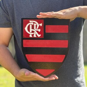 Peut inclure: Un panneau en forme de bouclier noir et rouge avec un logo "CR" blanc dans la partie sup&eacute;rieure et des rayures horizontales rouges et noires dans la partie inf&eacute;rieure.