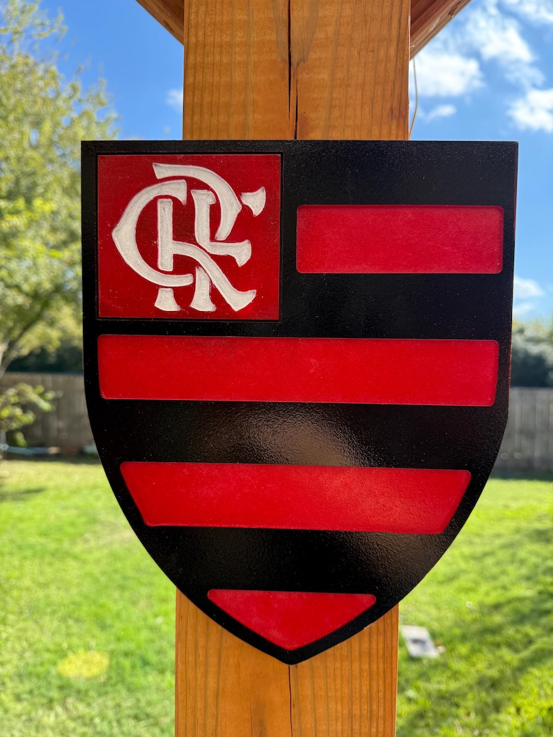 Peut inclure: Un panneau en forme de bouclier noir et rouge avec un monogramme blanc "CR" dans le coin sup&eacute;rieur gauche. Le bouclier comporte cinq bandes horizontales rouges sur fond noir.