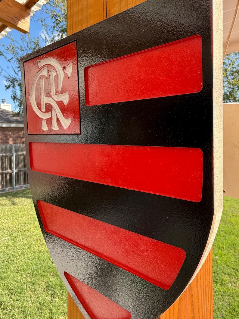 Peut inclure: Un panneau en forme de bouclier noir et rouge avec un logo blanc "CR" dans le coin sup&eacute;rieur gauche. Le bouclier comporte cinq bandes horizontales rouges avec des bordures noires.