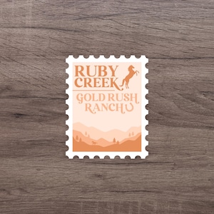 Puede incluir: Un diseño de sello postal con el texto "RUBY CREEK GOLD RUSH RANCH". El sello presenta una silueta de caballo encabritado y un paisaje de montañas en capas en tonos naranja y melocotón. El sello tiene un borde blanco con un borde perforado.