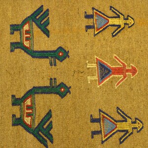 May include: Close-up of a woven textile with repeating patterns. The design features stylized bird-like figures in green, red, and blue, along with human-like figures in yellow, red, and blue. The background is a tan colour, with a red border on the right.