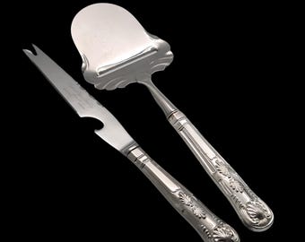 May include: A silver cheese knife and a silver cheese spreader with ornate handles.