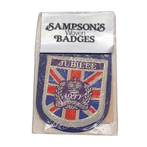 May include: A woven badge from Sampson's featuring a Union Jack design with the word "Jubilee" and the year "1977". The badge is in a clear plastic package. The text "Sampson's Woven Badges" is printed on the packaging.