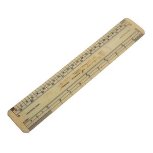 May include: A rectangular off-white Armstrong Scale ruler featuring printed black numerical markings and grid lines. The text reads Armstrong Scale, London, and Made in England. The ruler displays imperial inch measurements along the edge.