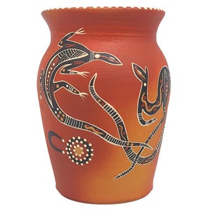 May include: A terracotta-colored vase with a wide mouth and a textured rim. The vase features a hand-painted design of stylized lizards and other abstract shapes in black, white, and brown. The background fades from orange to yellow.