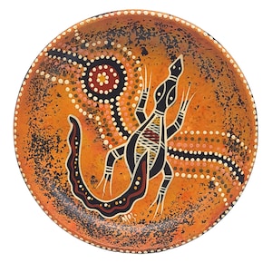 May include: Round orange decorative plate with a black lizard design. The plate features a dot-painted background with white, black, and red accents. The lizard has a detailed pattern in its body.