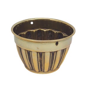 May include: A gold-coloured metal hanging planter with a fluted design. The planter has a hole at the top for hanging.