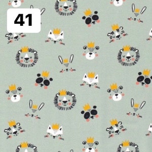Pode incluir: Um tecido verde claro com um padr&atilde;o repetido de animais de desenho animado usando coroas. Os animais incluem le&otilde;es, pandas, raposas, tigres e coelhos. O n&uacute;mero "41" est&aacute; em uma caixa branca no canto superior esquerdo.