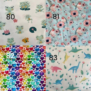 Pode incluir: Quatro amostras de tecido com diferentes padr&otilde;es. Uma apresenta sapos e o n&uacute;mero 80. Outra tem p&aacute;ssaros e flores com o n&uacute;mero 81. Uma terceira mostra cora&ccedil;&otilde;es coloridos com o n&uacute;mero 82. A &uacute;ltima mostra dinossauros e o n&uacute;mero 83.