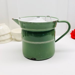 May include: A vintage green enamel pitcher with a white lid and a white stripe around the middle. The pitcher has a handle and a spout.