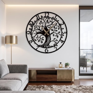 Puede incluir: Un gran reloj de pared circular con un diseño de metal negro recortado que representa un árbol con ramas y hojas extendidas. La esfera del reloj muestra números arábigos negros del uno al doce y tiene dos manecillas finas de color dorado.