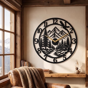 May include: A circular black metal wall clock featuring a cutout design of a mountain range, pine trees, a small cabin, and a flying eagle. The clock has gold-colored hands and large black numerals from one to twelve around the outer frame.