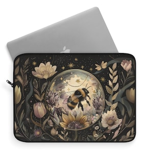 May include: A black laptop sleeve with a floral design featuring a bumblebee inside a glass orb. The orb is surrounded by flowers and stars on a dark background.