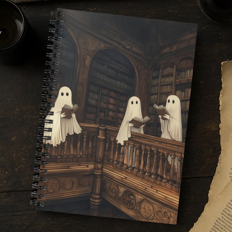 May include: Spiral-bound notebook featuring a spooky illustration of three ghosts reading books in a library. The artwork is in shades of brown and beige, with a detailed depiction of bookshelves and a wooden staircase. The cover art has a vintage, gothic aesthetic.