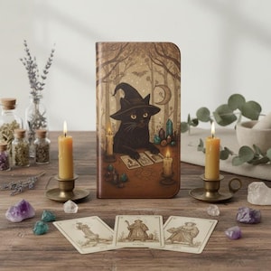 May include: A brown leather phone case featuring a black cat wearing a witch hat, surrounded by candles and tarot cards. The case has a forest scene background with a crescent moon and crystals. Tarot cards are laid out in front of the case.