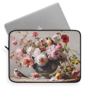 May include: A laptop sleeve featuring a vintage still life painting of a bouquet of pink and white peonies, roses, and other flowers in a blue and white porcelain vase. Two small birds are perched on the table, one yellow and one gray.