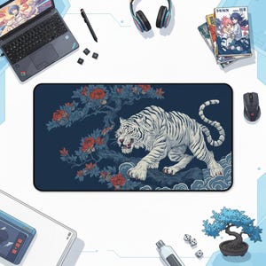 Könnte beinhalten: Rechteckige Schreibtischunterlage mit einer Illustration eines weißen Tigers mit schwarzen Streifen, vor einem dunkelblauen Hintergrund mit roten Blumen und blauem Laub. Die Unterlage ist von einem Laptop, Kopfhörern und anderem Schreibtischzubehör umgeben.