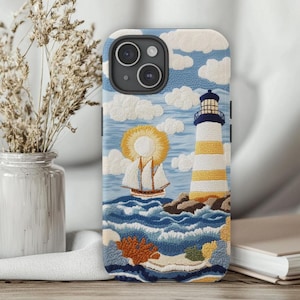 Może przedstawiać: Etui na telefon z haftowanym wzorem latarni morskiej, żaglówki i fal oceanicznych. Wzór jest w odcieniach niebieskiego, żółtego i białego.