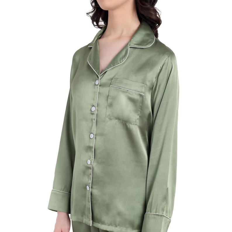 Women dressed in elegant satin pajama sets in Olive and white, each personalized with embroidered names or initials. They pose together in a cozy, well-lit bedroom setting, showcasing the luxurious and stylish design, ideal for special occasions.