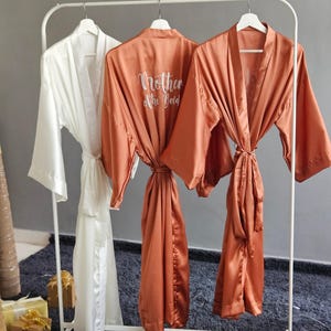 Bridesmaid robes in Long ankle or calf lengths in Burnt Orange and White soft silky satin with personalization text.