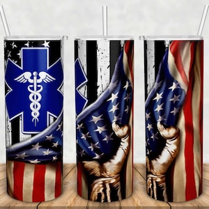 Puede incluir: Un vaso de acero inoxidable con un s&iacute;mbolo m&eacute;dico azul y blanco y un dise&ntilde;o de bandera estadounidense. La bandera est&aacute; drapeada sobre el vaso y parece estar sostenida por una mano.