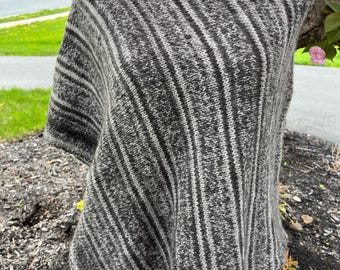 May include: A grey and white striped knitted poncho with a slouchy, oversized fit.