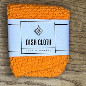 May include: Orange knitted dishcloth with a white label that reads "DISH CLOTH 100% HANDMADE".
