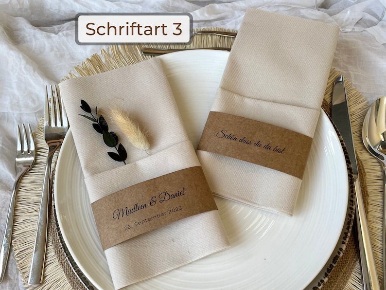 Kraftpapier Banderolen, die um Servietten gebunden sind in einer verspielten Schriftart.