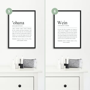 May include: Two framed prints with black frames and white backgrounds. The print on the left has the word 'ohana' in bold black text with a definition in smaller text. The print on the right has the word 'Wein' in bold black text with a definition in smaller text.