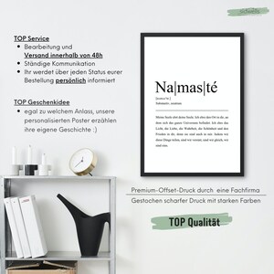 May include: A black and white print with the word "Na mas te" in bold, defined as a noun in German. The text below explains the meaning of the word in English. The print is framed in a black frame and is hanging on a white wall.