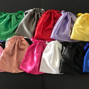 May include: Assortment of 12 colourful satin drawstring bags. The bags are made of soft, silky fabric and come in a variety of colours, including red, green, blue, yellow, pink, purple, white, black, and grey.