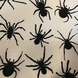 May include: A white fabric with a repeating pattern of black spider silhouettes.