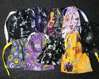 May include: Nine Halloween-themed drawstring bags in various colors and patterns. The bags feature designs of skeletons, potion bottles, spiders, and other spooky imagery.