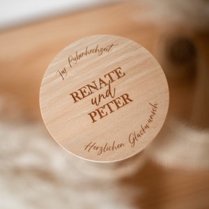 May include: A wooden round plaque with the text "Zur Rubinhochzeit Renate und Peter Herzlichen Glückwunsch" engraved on it.