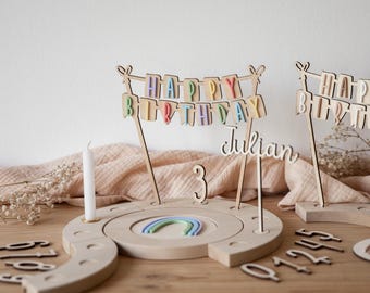 May include: Wooden birthday cake topper set with a rainbow, a candle, and a banner that says "Happy Birthday Julian". The set also includes a number 3 and a set of numbers 0-9.