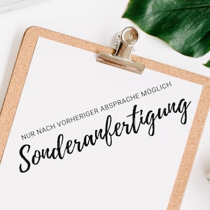 May include: A white sheet of paper with the text "NUR NACH VORHERIGER ABSPRACHE MÖGLICH Sonderanfertigung" on a corkboard with a silver binder clip.