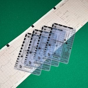 May include: Four clear plastic ECG measurement rulers with black markings. The rulers measure PR, QRS, QT, and ST intervals in seconds. The rulers also measure heart rate in beats per minute. The rulers are labeled "For educational purposes only" and "star-resources.co.uk".