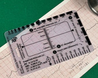 May include: A clear plastic ruler for measuring heart rate, PR, QRS, QT, and ST intervals on an electrocardiogram (ECG). The ruler has markings for seconds, millimeters, and heart rate in beats per minute. The ruler also includes expected intervals for PR, QRS, QT, and ST segments.