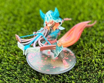 May include: A blue and orange figurine of a fox-like creature holding a crossbow. The figurine is standing on a round base with a pink and white floral design.
